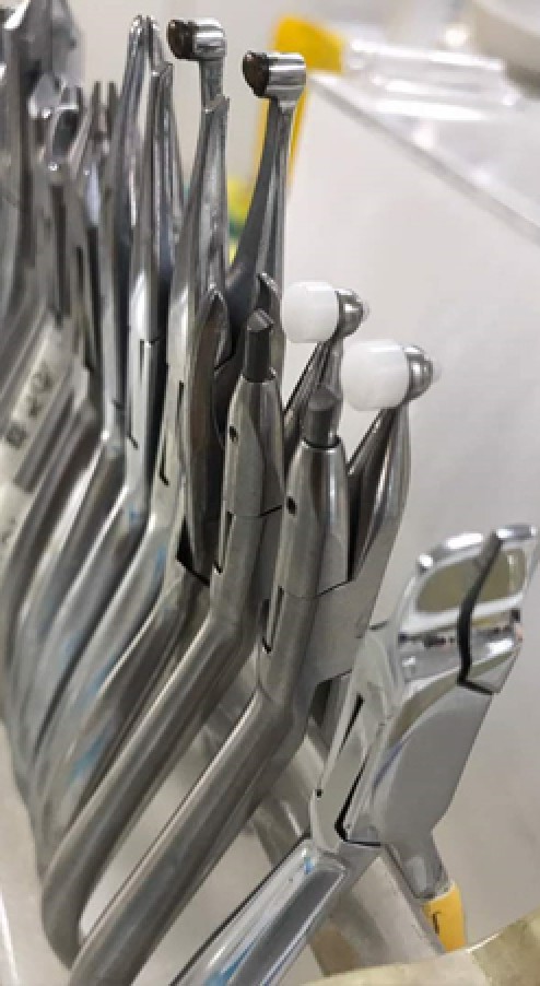 Orthodontic pliers held upright in an instrument rack, ready for inspection and packing